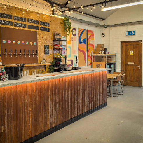 Inside the brewery bar at Crooked River Brewing Co in Keswick with cask ales on tap and a wooden bar in the foreground