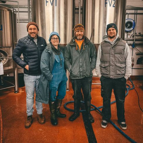 Four people standing in front of the brewing machines at Crooked River Brewing Co