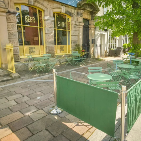 The outside of a bar in Cockermouth with green tables and chairs on the street outside