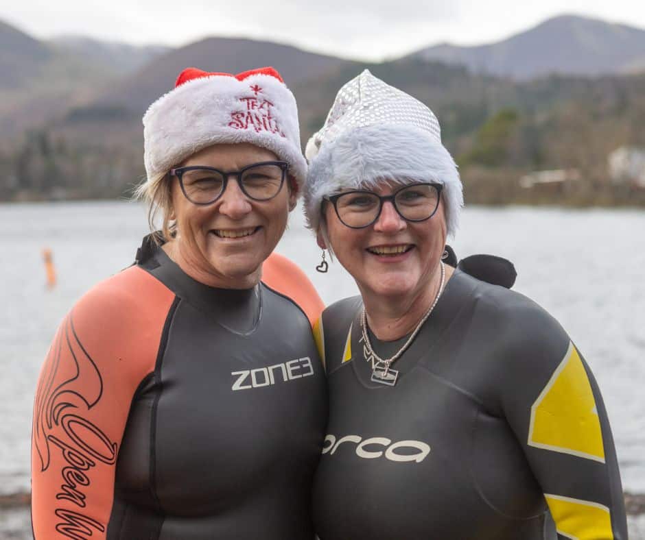Two women wearing wetsuits and Santa hats for our New Year's Day Dip 2026