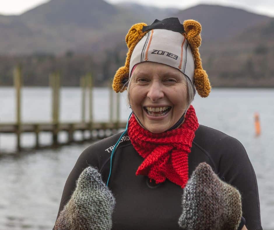 Woman in wetsuit, reindeer antlers and scarf before entering Derwentwater