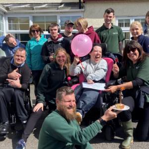 The team and guests celebrating Francesca's 20th visit with cake and balloons