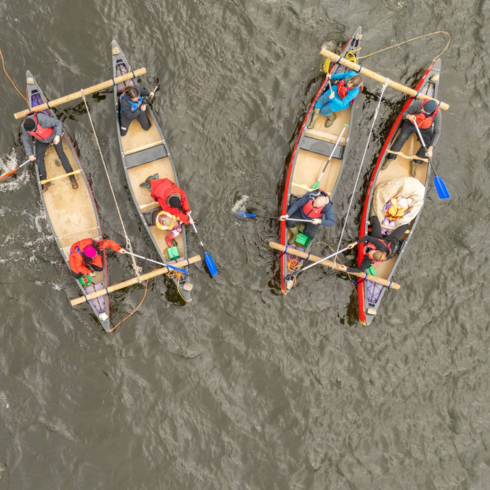 Aerial view of two sets of canoes lashed together with paddlers in them