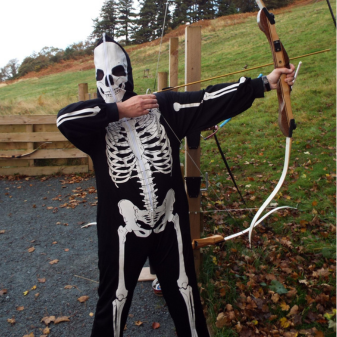 Boy in skeleton costume knocking a bow and arrow