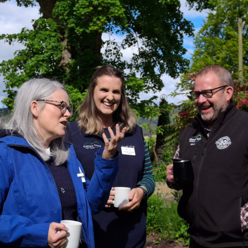 A woman talking and gesturing with a younger smiling women next to her and a laughing man to the right