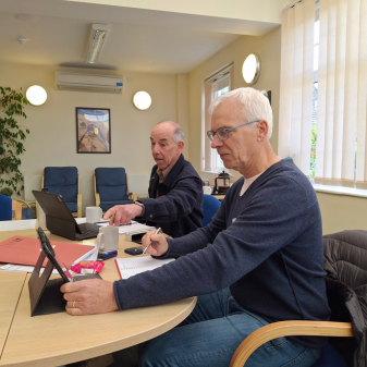 Two men in a conference room looking at laptops