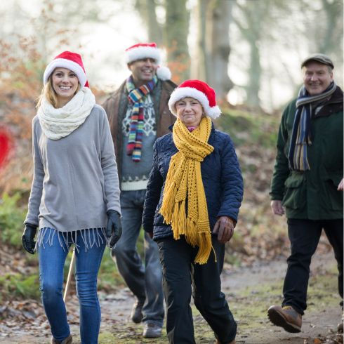 Group of adults in Santa hats walking in winter in the woods