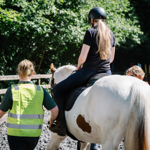 Woman on a horse being led by volunteers