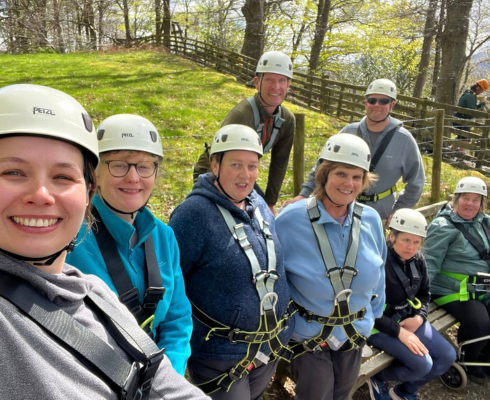 Group of mixed ability adults in helmets waiting to go on the zip wire