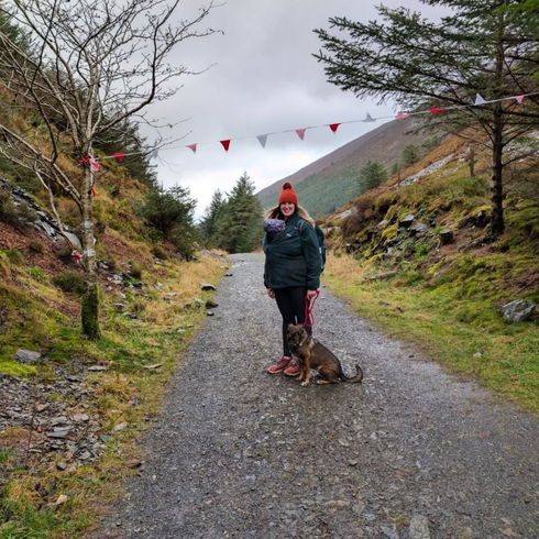 Woman on a path with bunting above her and a dog at her feet
