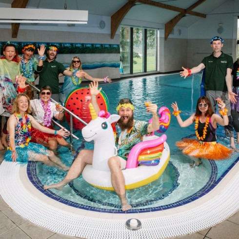 Calvert staff in hula and beach themed attire posing in the swimming pool