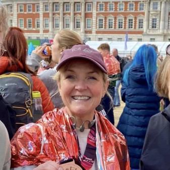 Woman smiling after completing the London Marathon with her medal around her neck surrounded by finishers
