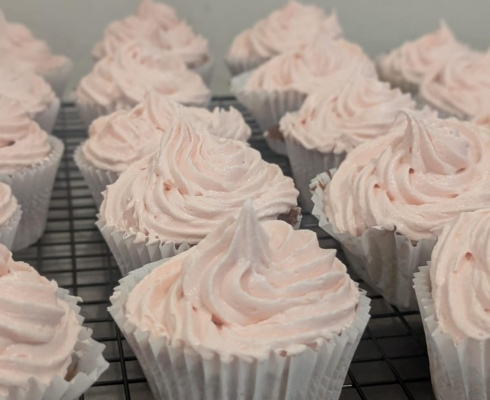 Close up of a tray of cupcakes with pink icing piped on top