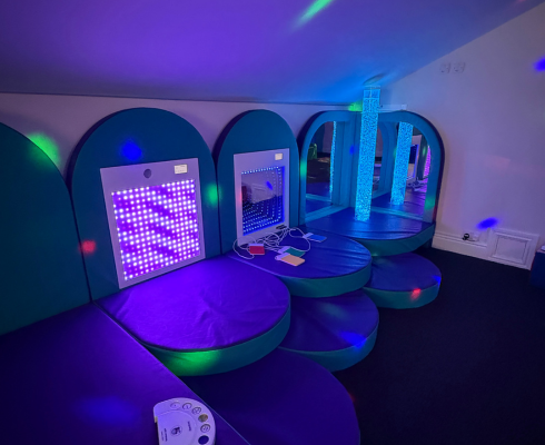 Sensory room showing light tunnel interactive toys, coloured spotlights and padded cushions