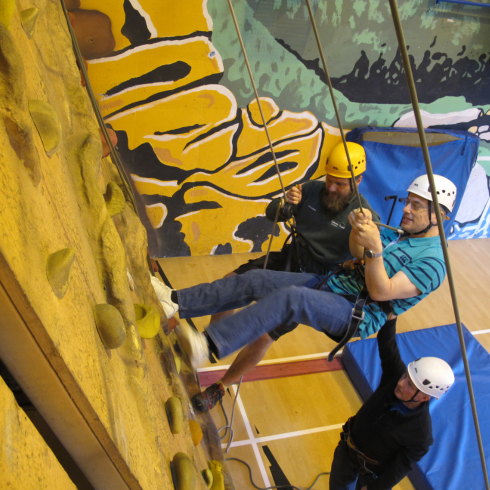 Man abseiling down indoor climbing wall with instructor