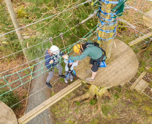 Aerial shot of the high ropes course with two people navigating a wire bridge