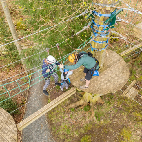 Aerial shot of the high ropes course with two people navigating a wire bridge
