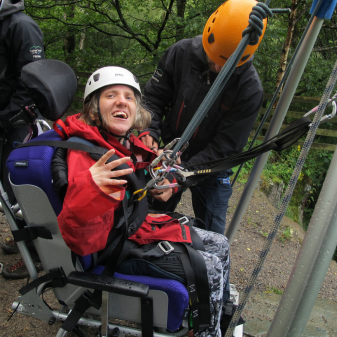 Woman in wheelchair with ropes and harness for abseiling