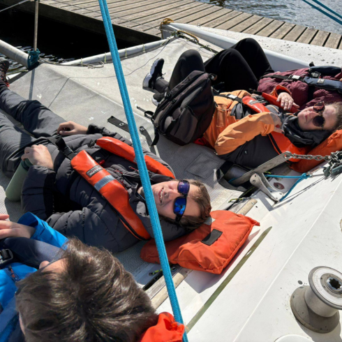 Group lying on cargo nets pictured from above on a catamaran