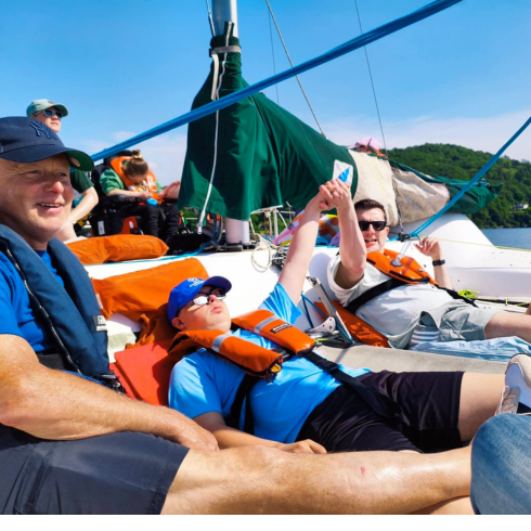 Group sitting on the cargo nets of a catamaran on Windermere