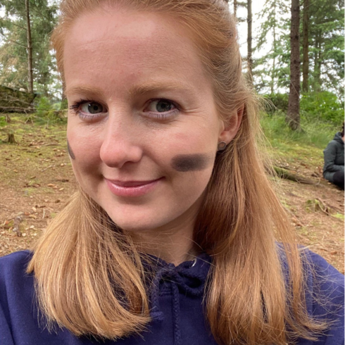 Closeup of a woman with streaks of charcoal on her cheeks