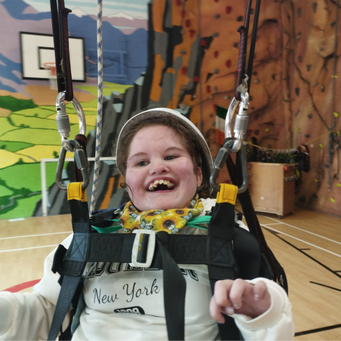 Young girl smiling in a swing in an indoor sports hall