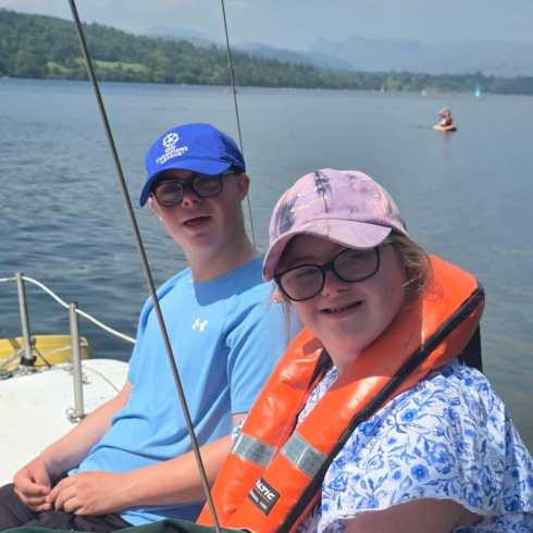 Two young people in buoyancy aids smiling on a catamaran