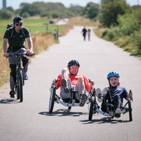 Man and girl on KMX bikes with instructor cycling beside them