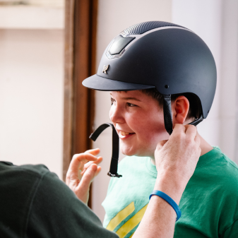 Young man having his helmet fitted at Calvert Stables