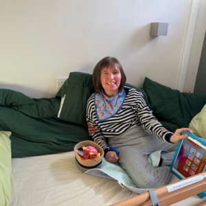 Woman relaxing in her room on a profiling bed with device and toys in front
