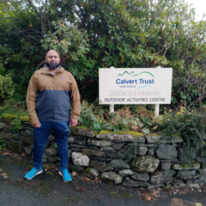 Man posing next to the Calvert entrance sign